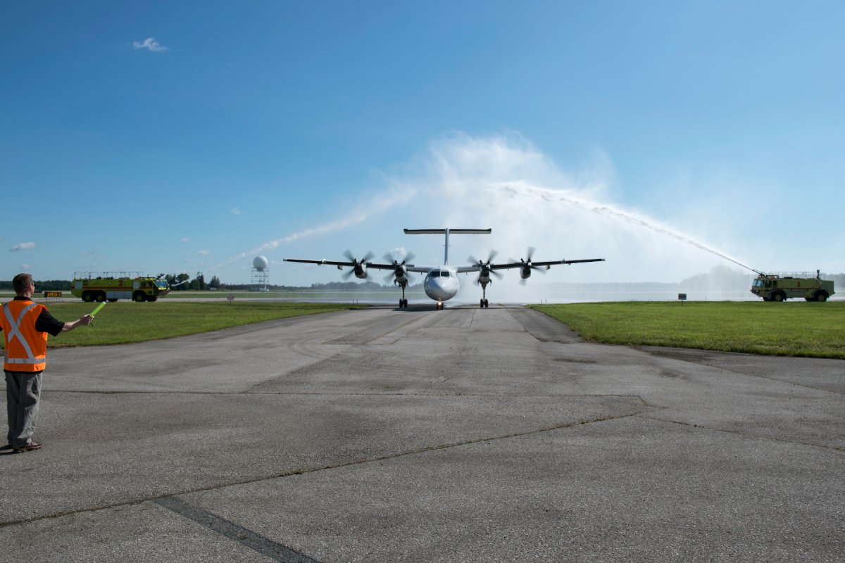 a de Havilland Canada DHC-7 (Dash 7) donated by Trans Capital Air Ltd., receives a water-cannon salute as it arrives at the Norton Wolf School of Aviation Technology.