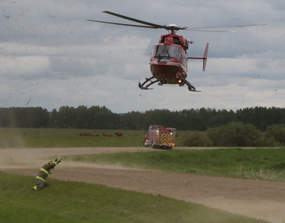 A firefighter helping a STARS air ambulance helicopter land at a collision north of Rimbey, Alta. on June 14, 2017. 