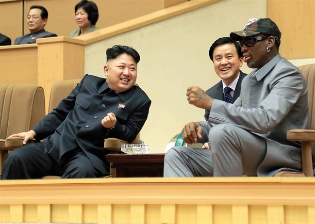Kim Jong Un smiling beside Dennis Rodman as several others watch on.