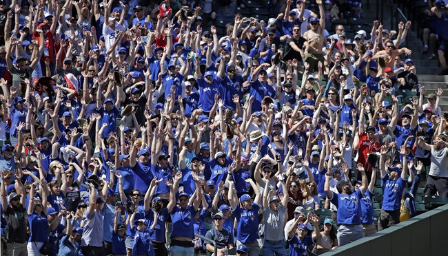 Fans, many wearing Toronto Blue Jays' blue shirts, stand as a "wave" rolls through the stadium in the seventh inning of a baseball game against the Seattle Mariners, Sunday, June 11, 2017, in Seattle. (AP Photo/Elaine Thompson).