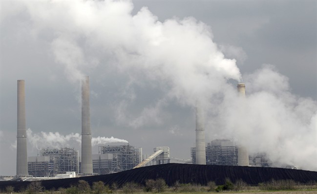 In this March 16, 2011 file photo, exhaust rises from smokestacks in front of piles of coal at NRG Energy's W.A. Parish Electric Generating Station in Thompsons, Texas. President Donald Trump's recommendation of a former coal-industry lobbyist to serve as the second-highest ranking official at the EPA has been approved.