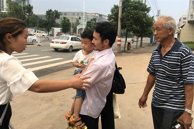 Chinese labor activist Hua Haifeng, center, carries his son Bobo chats with his sister Hua Xiaoqin, left, as they leave a police station.