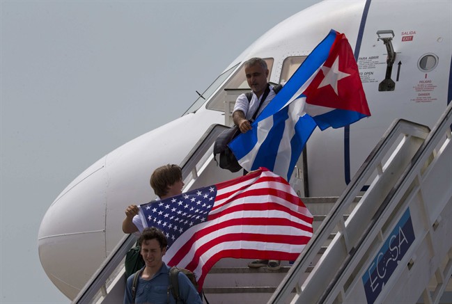 In this Aug. 31, 2016 file photo, two passengers deplane from JetBlue flight 387 waving a United States, and Cuban national flag, in Santa Clara. 