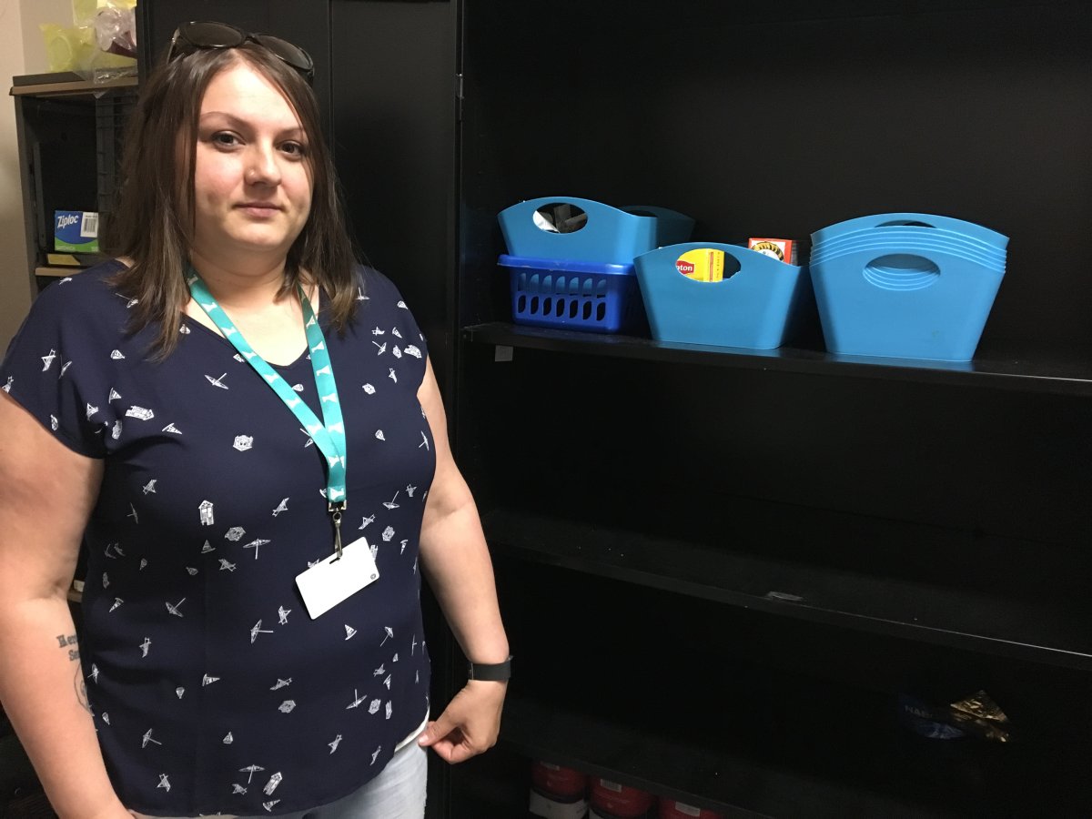 Lisa Ryan with the YMCA ReConnect program stands next to very empty shelves of food at the YMCA of Greater Moncton. 
