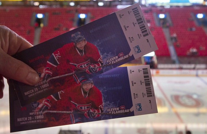 In this Feb. 2013 file photo a man holds up tickets prior to an NHL hockey game between the Montreal Canadiens and the Toronto Maple Leafs at the Bell Centre in Montreal. Season ticket-holders will now have to pay to print their tickets, with the team citing security, ease of use and environmental sustainability as reasons for the change. Saturday, July 22, 2017.