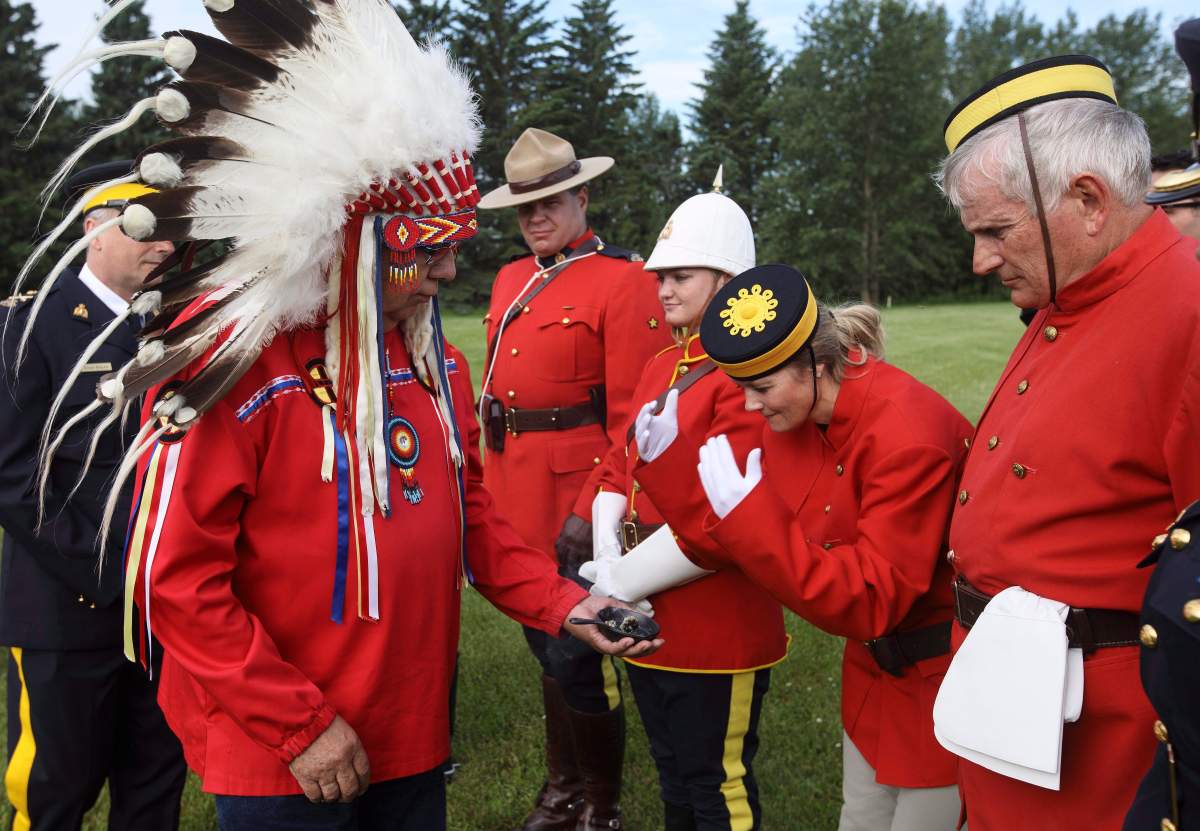 RCMP take part in a smudging ceremony before riding in the re-enactment of the March West, near Fort Saskatchewan, Alta., on June 30, 2017.