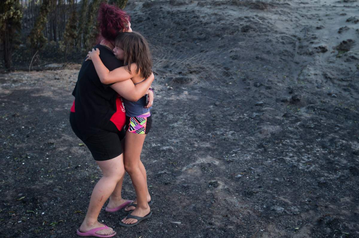 Kelsey Thorne holds her daughter Nevaeh Porter, 8, as they both cry after viewing the remains of their home where they lived with her parents that was destroyed by wildfire on the Ashcroft First Nation, near Ashcroft, B.C., late Sunday July 9, 2017. THE CANADIAN PRESS/Darryl Dyck