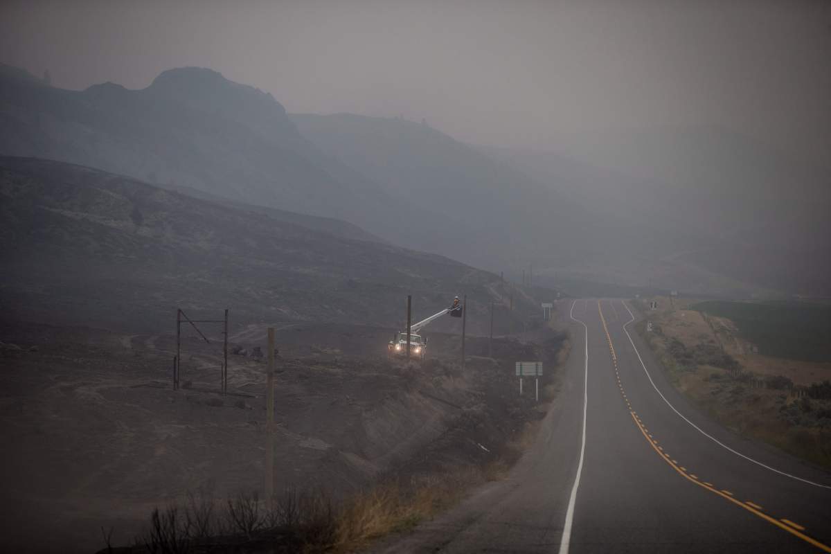 B.C. Hydro workers repair power lines that were damaged by wildfire as smoke and dirt blows in the air near Ashcroft, B.C., on Monday, July 10, 2017. More than 200 wildfires are burning in the province and an estimated 14,000 people have been evacuated from their homes. THE CANADIAN PRESS/Darryl Dyck