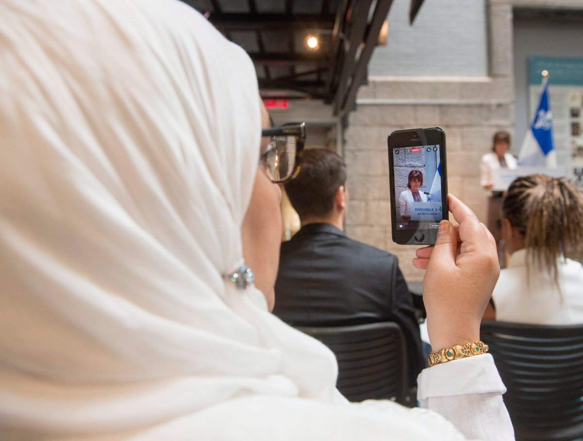 A woman records on her phone as Quebec Immigration, Diversity and Inclusiveness Minister Kathleen Weil makes an announcement about the fight against systemic discrimination and racism on July 20, 2017 in Montreal.