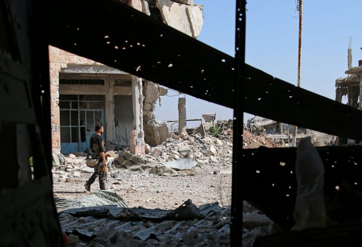 A Free Syrian Army fighter carries his weapon as he walks past damaged buildings in a rebel-held part of the southern city of Deraa on July 9.