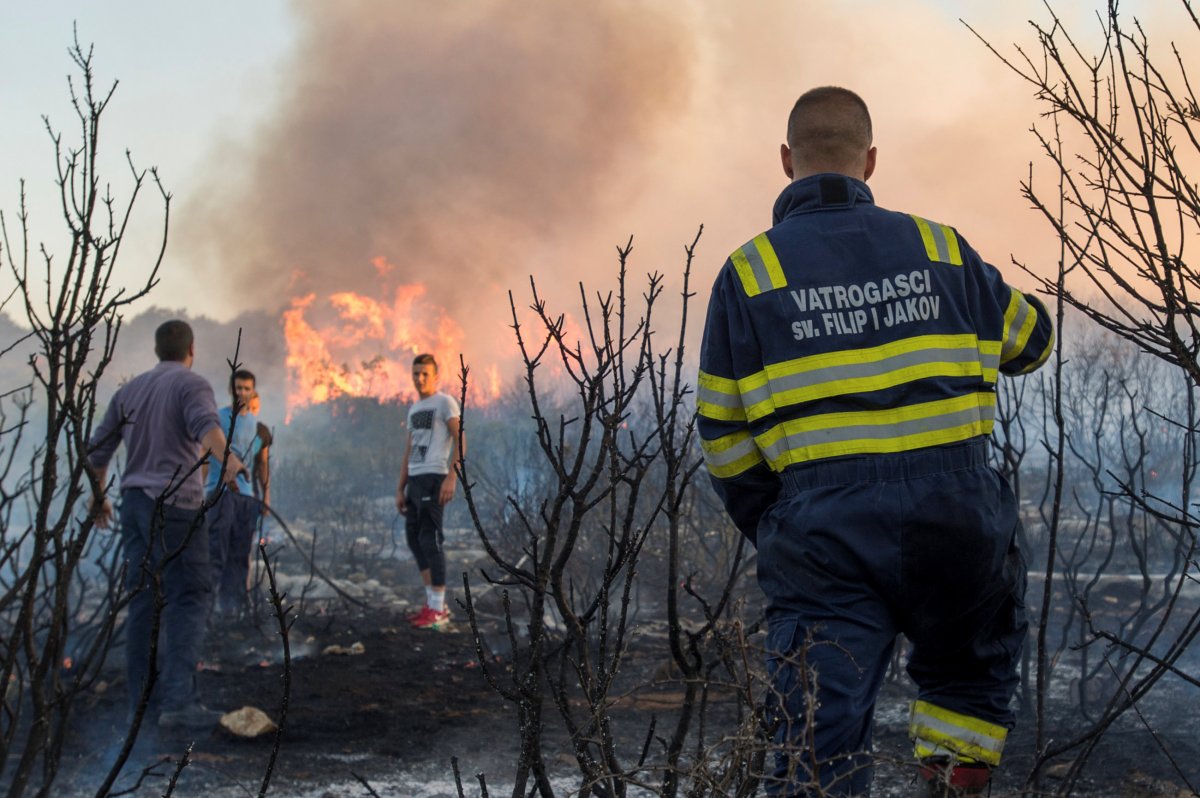 A firefighter and local residents try to extinguish a forest fire near Zadar, Croatia Sunday.
