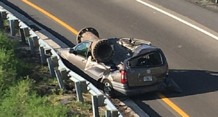 A van is shown with a piece of scrap metal on its roof in Orange County, Florida on Saturday. The scrap metal fell from a truck that had lost control and overturned on an overpass.