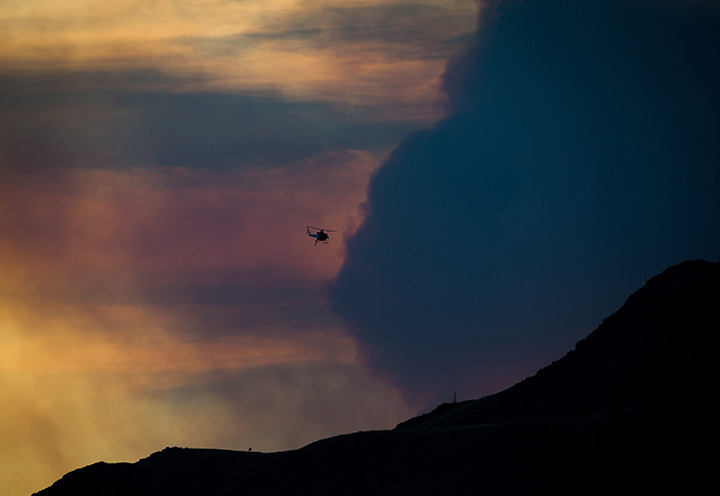 Smoke fills the air as a firefighting helicopter near Ashcroft, B.C., at sunset on Friday July 7, 2017.