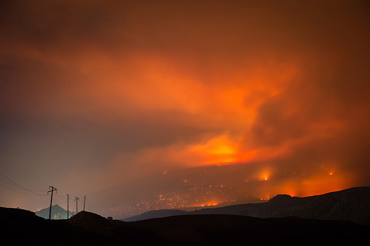 A wildfire burns on a mountain in the distance east of Cache Creek, B.C., in the early morning hours of Monday July 10, 2017.