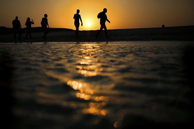 In this file picture taken Thursday, Aug. 20, 2015, tourists walk on the Giftun Island beach as the sun sets over the Red Sea in Hurghada, Egypt. 