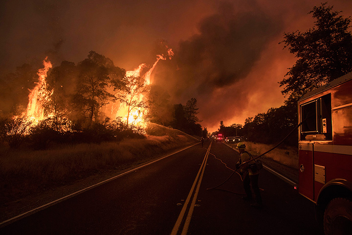 A firefighter battles a wildfire as it threatens to jump a street near Oroville, Calif., on Saturday, July 8, 2017.