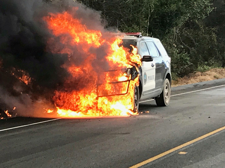 A police vehicle parked on a highway is engulfed by flames of the Whittier wildfire near Santa Ynez, California on July 9, 2017.