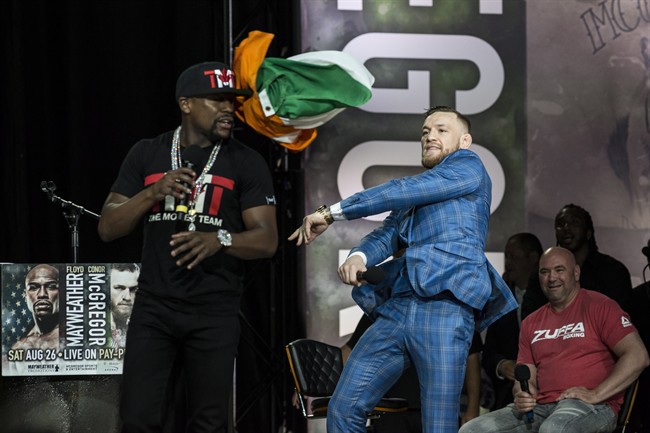 Conor McGregor, right, throws an Irish flag at Floyd Mayweather during a promotional tour stop in Toronto on Wedneday, July 12, 2017, for their upcoming boxing match in Las Vegas. 