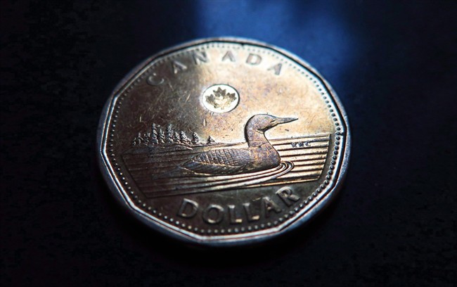 A loonie one-dollar coin is pictured on a dark backdrop