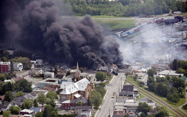 In this July 6, 2013, file photo, smoke rises from railway cars that were carrying crude oil after derailing in downtown Lac Megantic, Que. Quebec's environmental review agency says the majority of Lac-Megantic residents appear to favour keeping the railway track in the town, Tuesday, August 1, 2017.