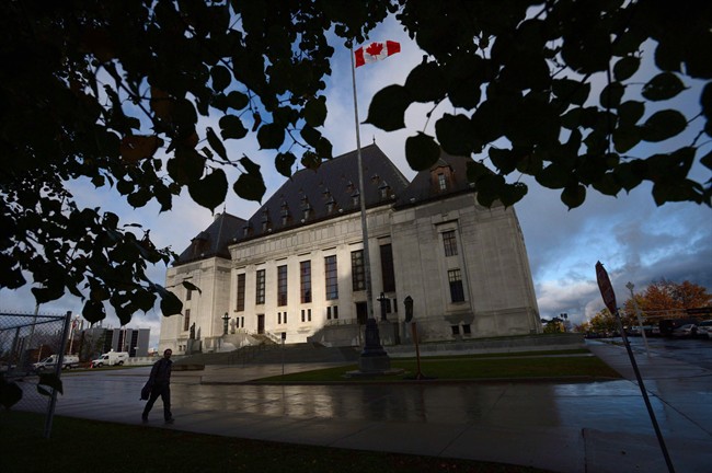 A pedestrian walks past the Supreme Court of Canada in Ottawa, Oct. 18, 2013. The Supreme Court will decide this morning whether the federal government can rely on National Energy Board reviews to fulfills its duty to consult indigenous communities before development can take place on their traditional territories. THE CANADIAN PRESS/Sean Kilpatrick.