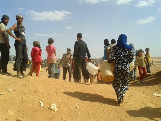 Syrian refugees gather for water at the informal Rukban camp for displaced Syrians, between the Jordan and Syria borders, on June 23, 2016. (AP Photo, File)