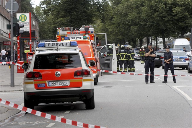 Police officers and fire engines stand in front of the supermarket in Hamburg, Germany, Friday, July 28, 2017, where a man with a knife fatally stabbed one person and wounded four others as he fled, police said.