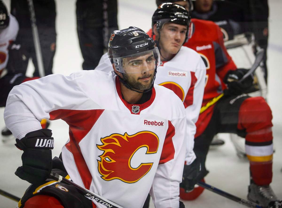 Calgary Flames’ Mark Giordano, centre, listens to instructions during an on-ice session on the second day of training camp in Calgary, Friday, Sept. 23, 2016.