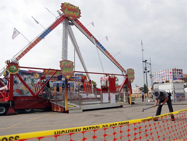 An Ohio State Highway Patrol trooper removes a ground spike from in front of the fire ball ride at the Ohio State Fair Thursday, July 27, 2017, in Columbus, Ohio. The fair opened Thursday but its amusement rides remained closed one day after Tyler Jarrell, 18, was killed and seven other people were injured when the thrill ride broke apart and flung people into the air. 