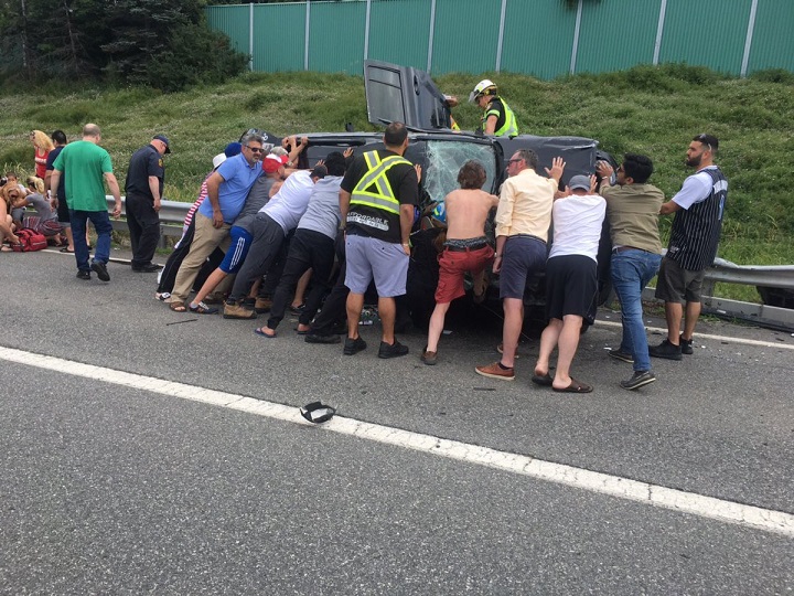 Civilians are seen holding up the vehicle involved in a rollover on Hwy. 403.