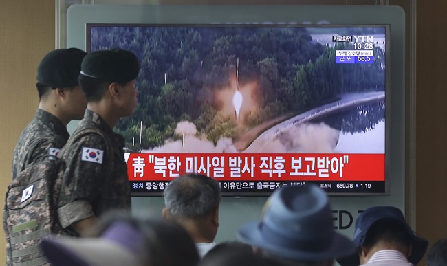 Army soldiers walk by a TV news program showing a file image of a missile being test-launched by North Korea at the Seoul Railway Station in Seoul, South Korea, Tuesday, July 4, 2017. 