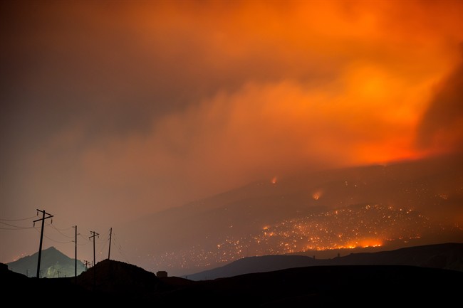 A wildfire burns on a mountain in the distance east of Cache Creek, B.C., in the early morning hours of Monday, July 10, 2017.