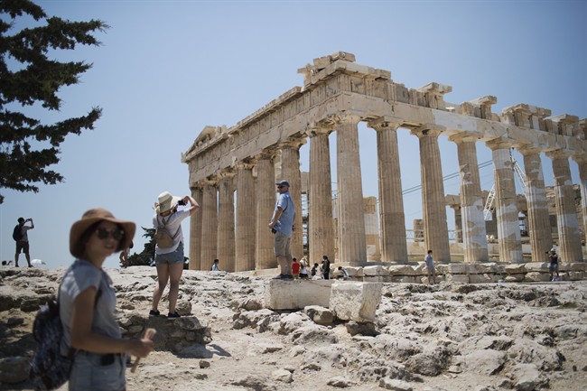Tourists take pictures in front of the fifth century BC Parthenon temple at the Acropolis hill in Athens, Wednesday, July 12, 2017.