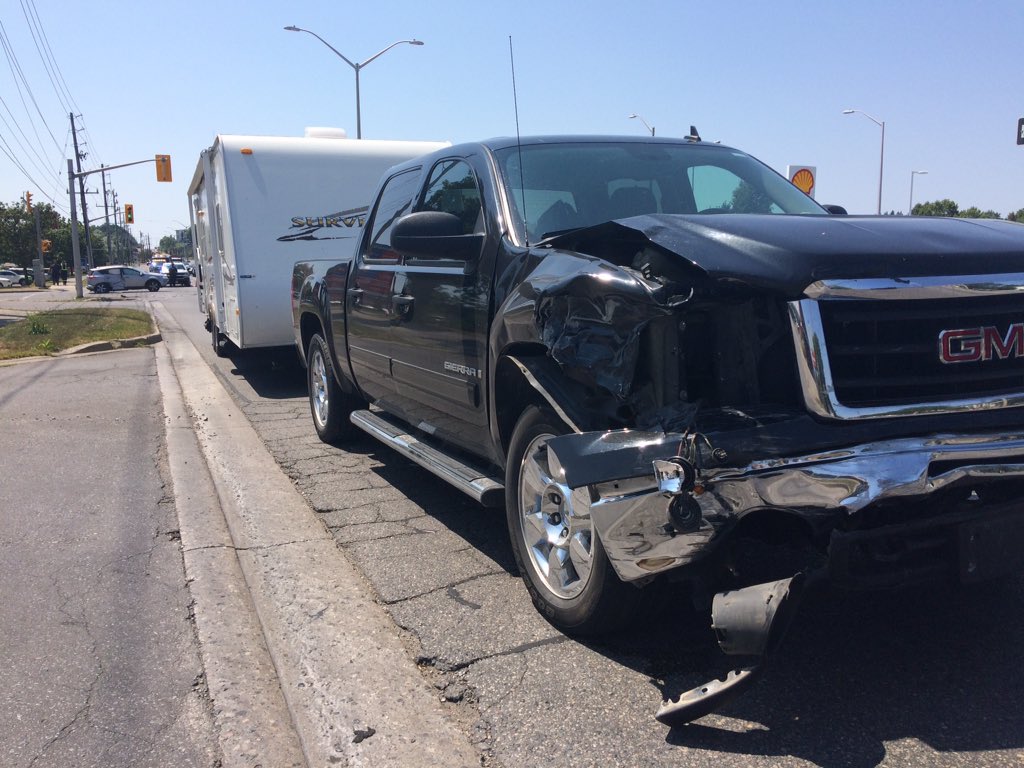 A GMC pick up truck pulling a trailer rests in eastbound lanes of Fanshawe Park Rd. E, while a damaged SUV sits in the middle of the intersection where it was struck.