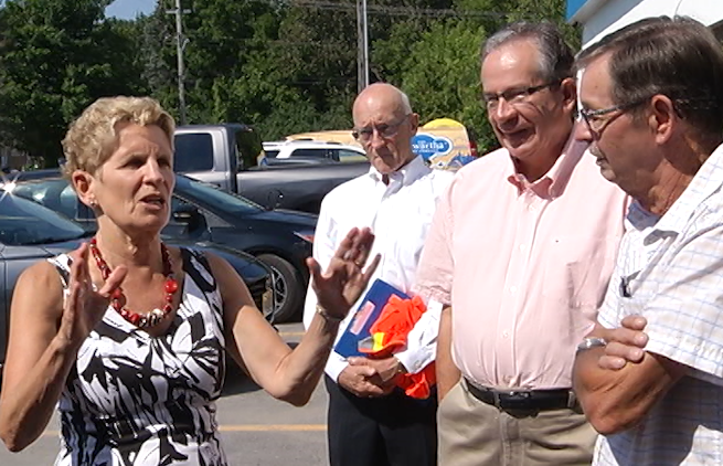 Premier Kathleen Wynne, left, announces funding for Kawartha Dairy on August 2, 2017, as VP and General Manager Blake Frazer. back, Peterborough MPP Jeff Leal, and a local realtor look on.