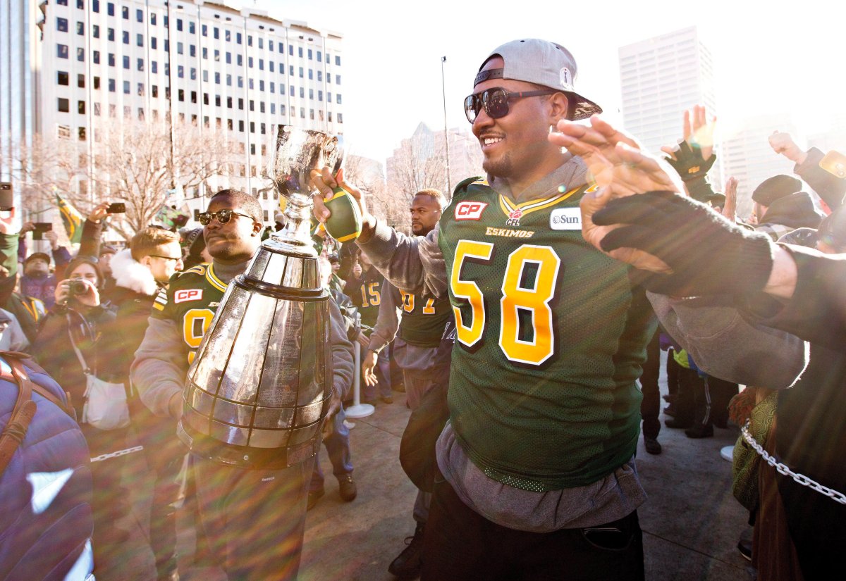 Edmonton Eskimos' Almondo Sewell (90) and Tony Washington (58) carry the Grey Cup to the stage during a fan rally for the Grey Cup champions, in Edmonton, Alta., on Tuesday December 1, 2015. The Eskimos defeated the Ottawa Redblacks 26-20 to win the 103rd Grey Cup in Winnipeg. 