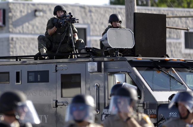 In this Aug. 9, 2014, file photo, a police tactical team moves in to disperse a group of protesters following the shooting of a young black man by a white policeman in Ferguson, Mo.

