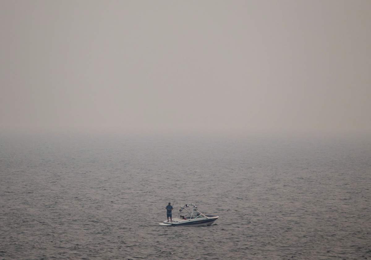 Thick smoke from wildfires fills the air as a man stands on a boat while fishing on Kamloops Lake west of Kamloops, B.C., on Tuesday August 1, 2017. Poor air quality persists throughout the southern half of British Columbia as tinder-dry conditions continue to fuel wildfires. 
