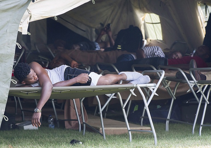 Asylum seekers rest in a tent at the Canada-United States border in Lacolle, Que., Thursday, August 10, 2017. THE CANADIAN PRESS/Graham Hughes