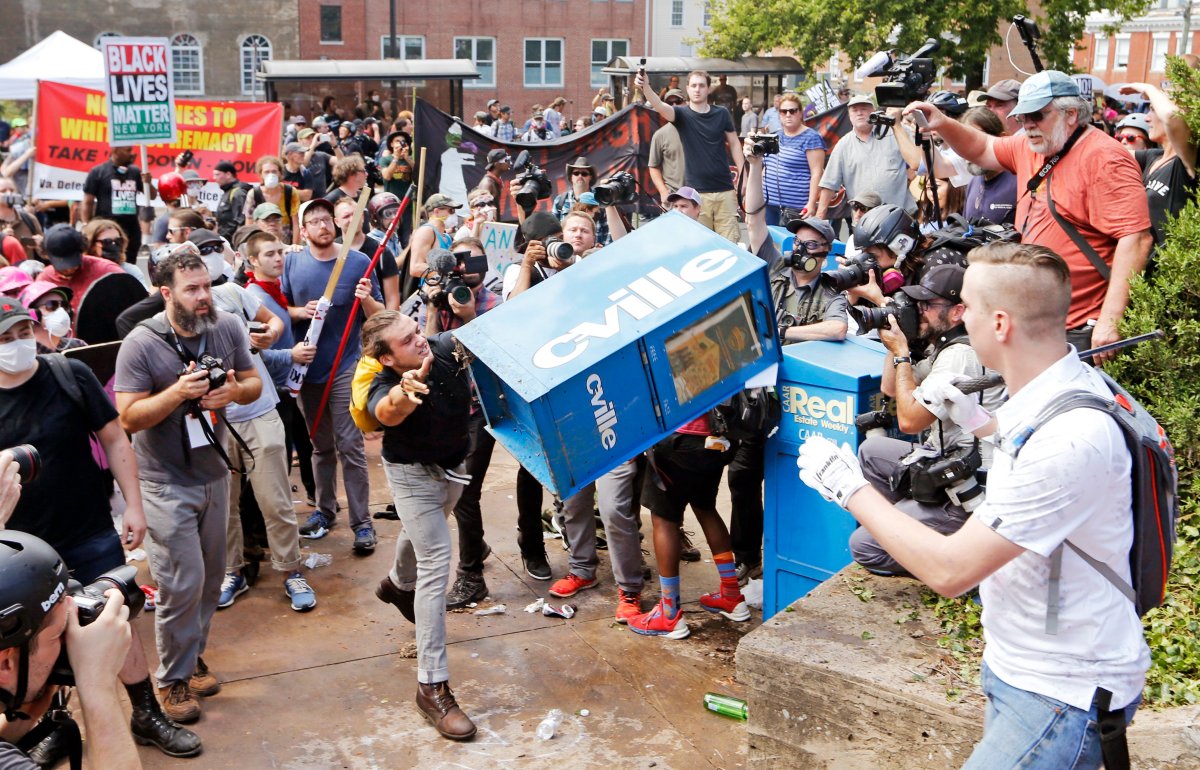 White nationalist demonstrators, right, clash with a counter-protester as he throws a newspaper box at the entrance to Lee Park in Charlottesville, Va., on Aug. 12, 2017.