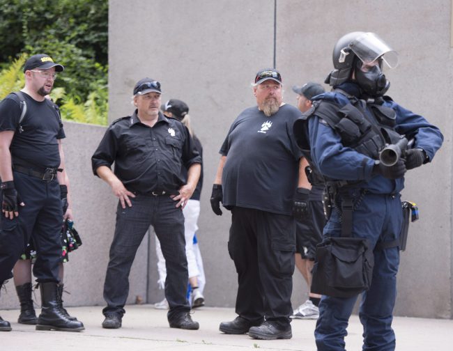 Members of far-right group “La Meute” stand behind a police line as left wing activists regroup during an anti-racism demonstration, in Quebec City on Sunday, August 20, 2017.