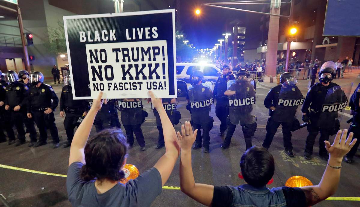 Protesters raise their hands after Phoenix police used tear gas outside the Phoenix Convention Center, Tuesday, Aug. 22, 2017, in Phoenix. Protests were held against President Donald Trump as he hosted a rally inside the convention center.