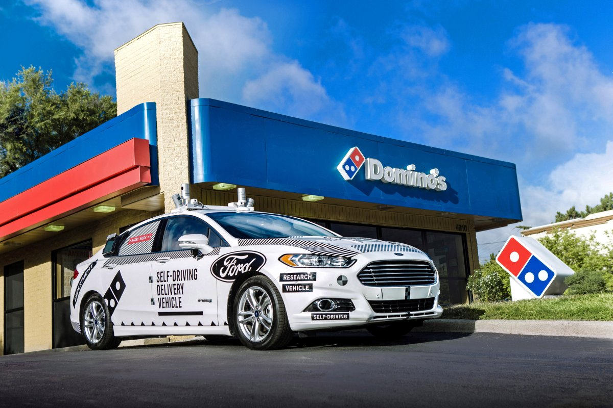A Ford self-driving delivery vehicle is pictured in front of a Domino's pizza restaurant in Michigan.