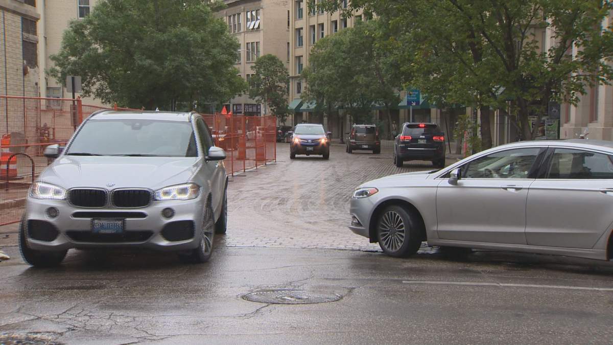 Barricades blocking in a sink hole making it difficult for drivers to squeeze on to the road.