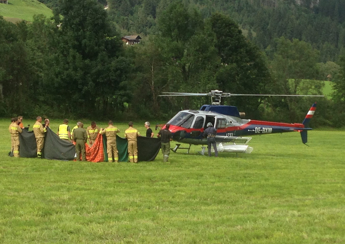 Rescue workers stand next to a police helicopter in Krimml in the Austrian province of Salzburg, Sunday, Aug. 27, 2017. T.