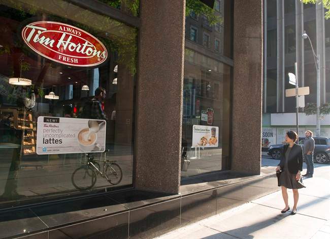 A woman walks pass a Tim Hortons in Toronto on Wednesday Aug. 2, 2017. Restaurant Brands International Inc. (TSX:QSR) says it has signed a deal with joint venture partner to take Tim Hortons to Spain. 
