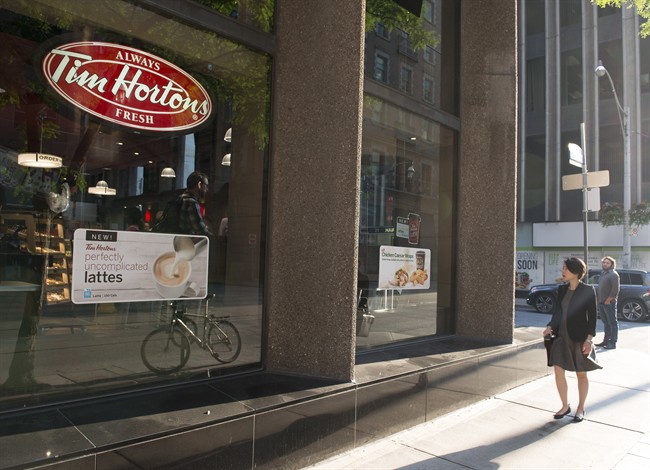 A woman walks pass a Tim Hortons in Toronto on Wednesday Aug. 2, 2017.