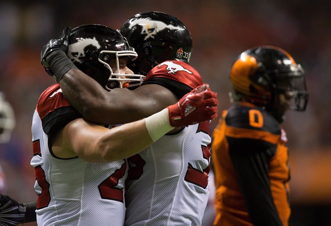 Calgary Stampeders' Rob Cote, left, and Jerome Messam celebrate Messam's touchdown as B.C. Lions' Loucheiz Purifoy, back right, walks to the sideline during the second half of a CFL football game in Vancouver on August 18, 2017.