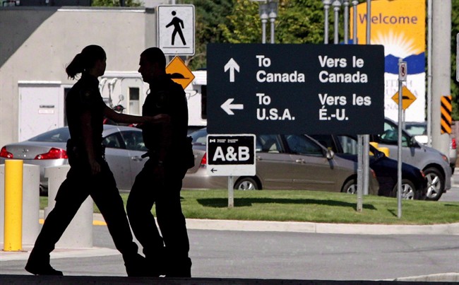 Canadian border guards are silhouetted as they replace each other at an inspection booth at the Douglas border crossing on the Canada-USA border in Surrey, B.C., on Thursday, August 20, 2009.
