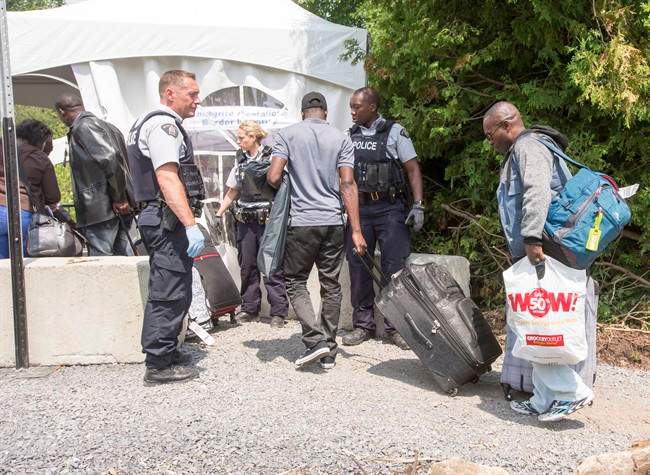 A group of asylum seekers cross the Canadian border at Champlain, N.Y., Friday, August 4, 2017. Prime Minister Justin Trudeau, long an outspoken champion of Canada's reputation for welcoming newcomers, added a bracing dose of reality Friday as he urged would-be migrants to respect the country's border with the United States.